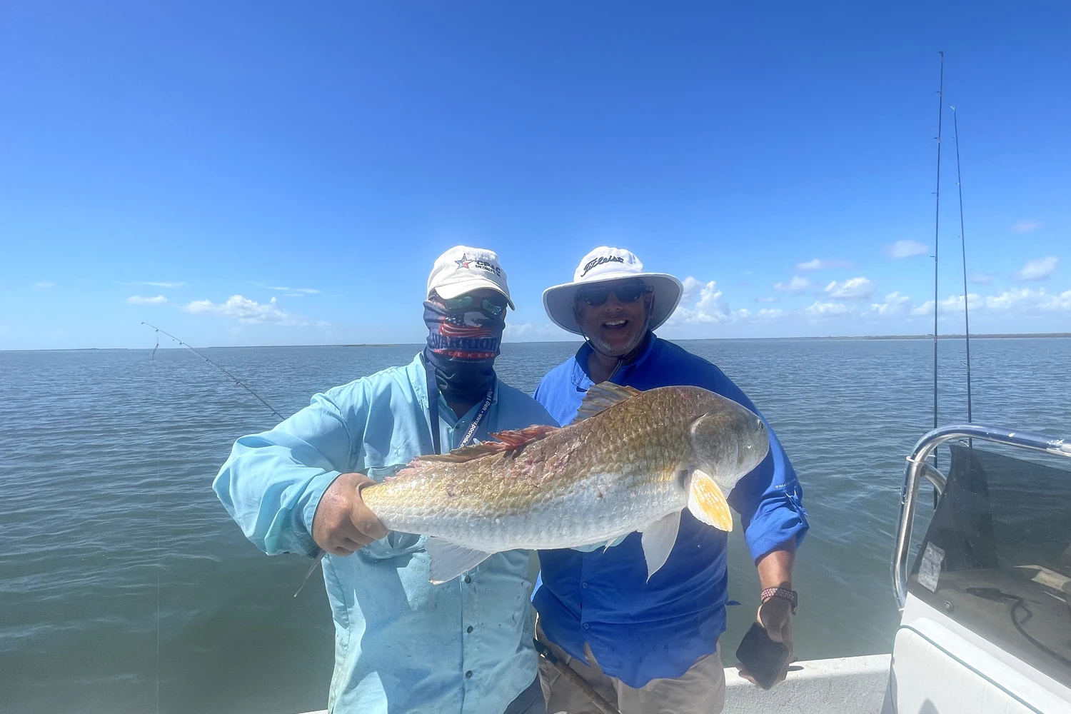 Anglers displaying a large redfish on the water