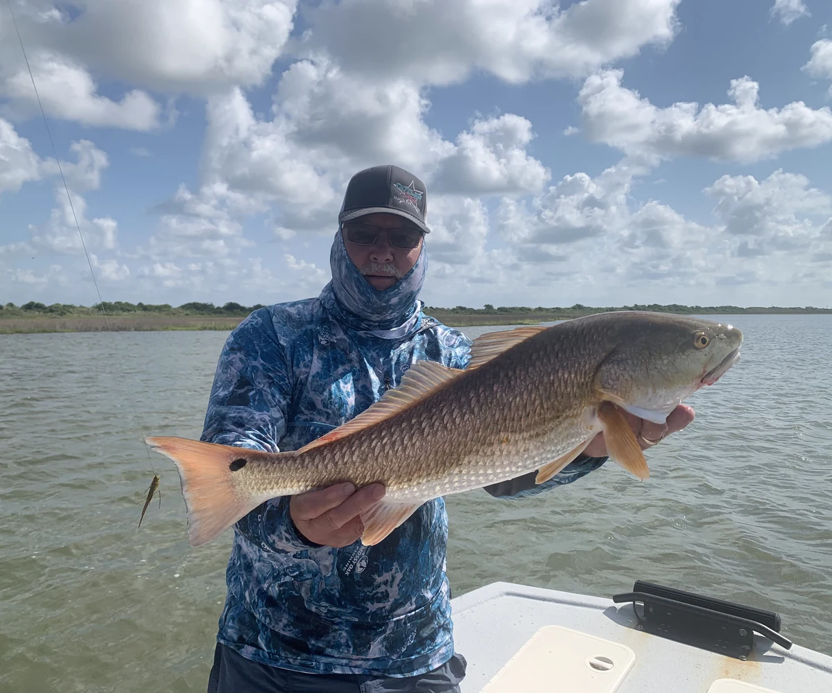 An angler holding a large redfish from the boat